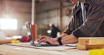 Hand, carpenter and reading in factory with laptop, research and review design for production. Man, typing and pc in workshop for carpentry, online blueprint and schedule for manufacturing furniture