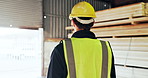 Man, carpenter and walking in workshop with helmet, inspection and timber production. Back, male person and supervisor in factory for carpentry, quality assurance and ppe for manufacturing furniture