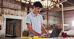 Man, typing and laptop in workshop for carpentry, research and review design for production. Person, reading and pc in factory with carpenter, online blueprint and policy for manufacturing furniture