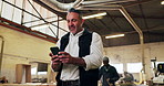 Man, carpenter and reading at workshop with phone, research and schedule for timber production. Mature person, walk and mobile at factory for carpentry, supplier approval and manufacturing furniture