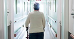 Walker, medical and back of old woman in hospital for rehabilitation, checkup or support. Healthcare appointment, osteoporosis and walking with senior person with a disability in clinic for recovery