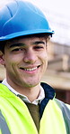 Construction site, engineer and man with smile outdoor for building development with helmet. Confidence, portrait and happy architect with renovation, about us or safety inspector with infrastructure