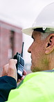 Man, engineer and radio at site for construction, inspection and discussion for architecture. Mature person, talk and tech at worksite for safety check, instructions and feedback on building progress