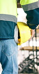 Engineer, helmet and hand of man walking at construction site for safety compliance, ppe and back. Person, foreman and hard hat for protocol, scaffolding and building development or maintenance