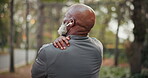 Shoulder pain, back and man outdoor for fitness, muscle tension or prepare for workout with music. Black person, senior with joint pressure or warm up for exercise, strain and earphones in nature