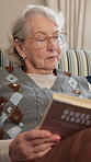 Elderly, woman and reading book in retirement home with glasses, relax and learning gardening tips. Calm, senior person and spectacles in living room with house plants novel, knowledge and insight.