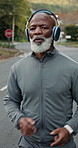 Exercise, headphones and running with black man outdoor on street for cardio training or workout. Fitness, music streaming and wellness with mature person in neighborhood for physical health activity