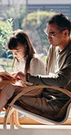 Father, help and reading book in home with Asian child, knowledge and learn for language development. Window, Japanese man and daughter in chair with kids novel, education and assistance for growth.