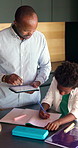Tablet, father and child with homework in kitchen for learning, development or education at house. Digital technology, writing and African kid with dad for mathematics quiz or studying in apartment.