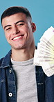 Man, face and money fan in studio for winnings, competition success and gambling payout with smile. Happy person, cash and confident on blue background with lottery jackpot, bonus income and euros