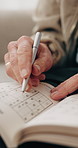 Senior, hands and writing with sudoku in home for number game, pattern or puzzle book. Elderly, male person or empty blocks with cognitive activity for problem solving, thinking or memory in house