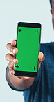 Man, hands and phone with green screen in studio for advertising app on a blue background. Male person, fitness and showing mobile smartphone display with chromakey for marketing on mockup space