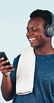 Laughing, fitness and black man with headphones in studio for music on a blue background. Active, male person or listening with smile, smartphone or app for funny workout, exercise or audio streaming