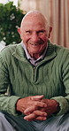 Wellness, face and old man in house with laugh, positive attitude or weekend break with unwind. Wellbeing, happy or elderly person on couch with funny joke, confidence and good mood in retirement.