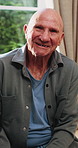 Smile, face and elderly man in home for wellness, relax and happy for comfort in retirement. Laugh, portrait and senior person at window with positive outlook, peace and good memories or nostalgia