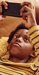 Phone, game and kid relax in home, interactive website and online entertainment on weekend. African boy, apartment and mobile gaming on couch at living room, play level and scroll app on internet