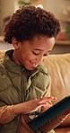 Smile, home and child with tablet for game, online entertainment or educational app. African boy, sofa and happy with tech for digital puzzle, scroll internet or browsing website for development