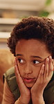 Sad, thinking and kid with depression in home, loneliness and bad memory with trauma. Reflection, unhappy child and African boy with anxiety, boredom or stress with mental health crisis in lounge