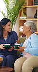 Caregiver, laugh and drinking coffee in nursing home with old woman, visit or joke for bonding together. Happy, senior person and nurse in retirement house with tea, talk and humor for funny story.