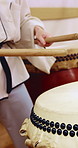 People, hands and drums with sticks in class for music production, sound or taiko tradition. Group, instrument and playing with percussion rhythm, culture or musical audition for performance together