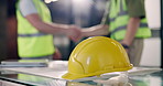 Hardhat, desk and construction workers on site with handshake for PPE or safety compliance. Helmet, people and civil engineer shaking hands with contractor for building approval, deal or agreement.