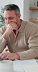 Man, laptop and thinking in home for finance, budget planning or asset management in kitchen. Mature person, document or checking invoices with tech for financial expenses and paperwork in house
