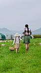 Back, mother and girl walking on chicken farm for bonding, livestock and basket of eggs. Farmer, parent and daughter holding hands in field with clipboard, agriculture and poultry for agro business
