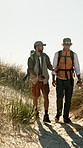 Hiking, men and friends walk in nature for travel, conversation or point for sightseeing on vacation. Trekking trip, adventure and people by ocean on journey, exploration and tourism on holiday