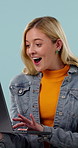 Excited, woman and surprise in studio with laptop, celebration and happy for giveaway promotion. Person, shock and cheering with computer, notification or online competition winner on blue background