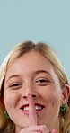 Smile, secret and face of woman in studio with confidential information, news or quiet voice. Space, whisper and portrait of person with finger on mouth for gossip or silence on blue background.