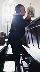 Man, kneeling and prayer in church with faith, funeral service and memorial ceremony in religion for death. Mourning, person and thinking of memory for respect, worship and grief in Christian chapel