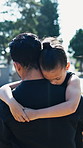 Child, hug and parent in graveyard for funeral, compassion or burial for death, support or crying with coffin. Girl, embrace or sad kid in cemetery for grief, loss or mourning with dad and empathy