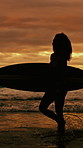Sunset, woman and walking at beach with surfboard, travel and adventure for summer holiday. Space, female person and surfer at sea with smile, getaway journey and water activity for tropical vacation