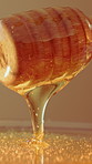 Wellness, dipper and honey in studio for nutrition, antibacterial properties and natural sugar. Raw, organic sweetener and stick on brown background for syrup additive, antioxidants and gut health