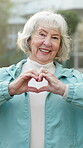 Happy, face and old woman with heart hands, outdoor and confident with love symbol or emoji gesture. Pensioner, portrait and senior person with smile for retirement, care sign and kindness on weekend