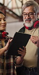 Carpenter, mentor and woman with tablet in workshop, discussion or planning for furniture production. Warehouse, artisan and people with technology, manufacturing and woodworking project on website
