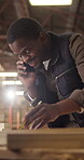 Carpenter, phone call and man in workshop, multitasking and talking with contact for project update. Woodworker, communication and black person with mobile, drawing and plan for furniture production