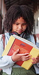 Reading, book and study with child in school hallway for education, knowledge and academy. Learning, literacy development and growth with student in corridor of campus for scholarship and project