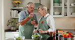 Taste, cooking and senior couple in home kitchen with wooden spoon, bonding and love. Happy, food and feeding for sauce and flavour with approval, people and teamwork in house for retirement