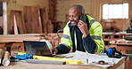 Laptop, man and happy with phone call in carpentry for shopfitting, custom furniture or update. Construction, mature black person and mobile contact in warehouse for layout design, tech and feedback