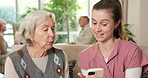 Old woman, caregiver and help with phone on sofa for managing contacts, explain site or learning. Senior, happy carer and teach mobile app for telehealth homepage, assisted living or digital literacy