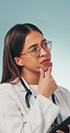 Confused, doctor and thinking in studio with tablet, medical research and brainstorming for decision. Healthcare worker, woman and doubt for diagnosis, problem solving and concern on blue background.