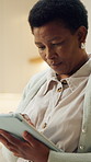 Black woman, tablet and reading in home for internet, news or blog post with online information. Technology, search and mature person with app to check article, newsletter and browsing website