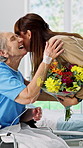 Senior, mom or adult daughter with flowers in hospital bed for family visit or patient in wheelchair. Elderly, mother and woman with bouquet, love or floral gift for healthcare, recovery or support