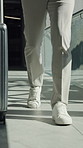 Person, walking and legs with suitcase in office building for business travel, opportunity or schedule. Employee, traveler or shoes with luggage for flight booking, work trip or commute in workplace