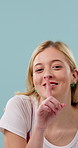 Smile, secret and face of woman in studio with confidential information, news or quiet voice. Happy, space and portrait of person with finger on mouth for gossip or silence on blue background.