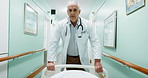 Emergency, walking and surgeon with bed in hospital for operation, icu or ER healthcare in hallway. Rush, man and medical worker with stretcher for surgery, treatment or support in clinic corridor.