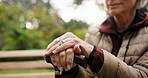 Hands, cane and old woman on bench in retirement for thinking, reflection and fresh air outdoor. Walking stick, break and elderly person with disability for wellness, memory and thoughtful in garden