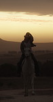 Sunset, woman and horse riding in countryside with hat, companion and bonding together on adventure. Evening, person or cowgirl travel outdoor in field with stallion, loyalty or animal care in Texas.