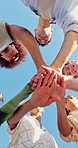 Below, stack and hands of friends with blue sky for support, friendship and bonding on holiday. Circle, huddle and men with women outdoor for collaboration, applause or connection on weekend together